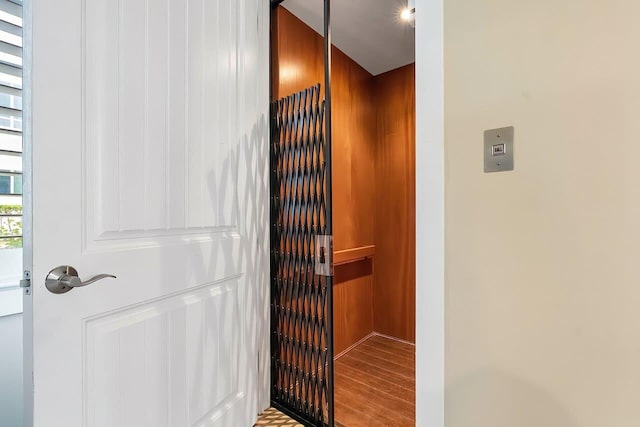 interior space with hardwood / wood-style floors, elevator, and wooden walls