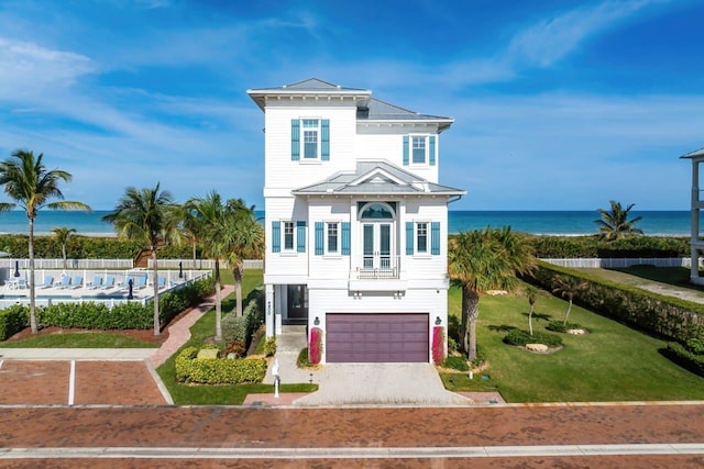 view of front of property featuring a garage, a water view, and a front yard