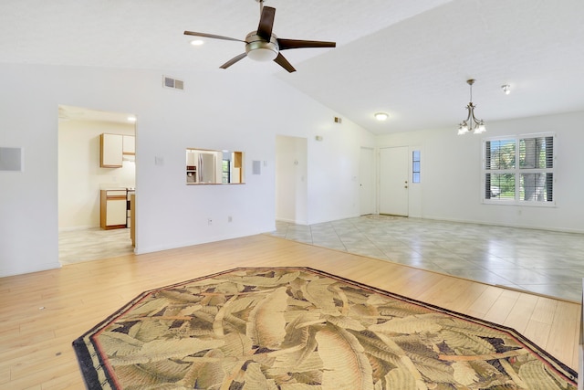 unfurnished living room with vaulted ceiling, ceiling fan with notable chandelier, and light hardwood / wood-style floors