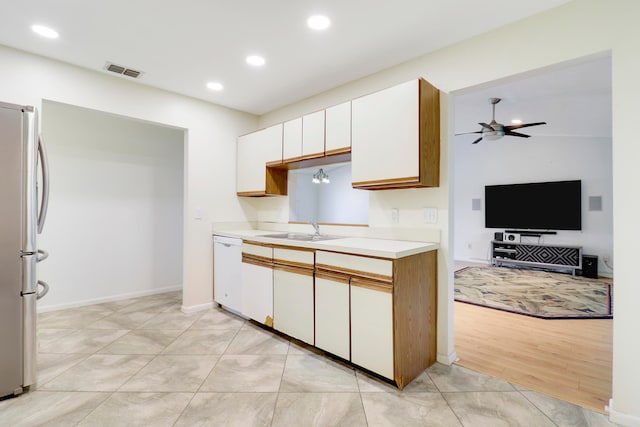 kitchen with dishwasher, light hardwood / wood-style flooring, sink, white cabinets, and stainless steel refrigerator