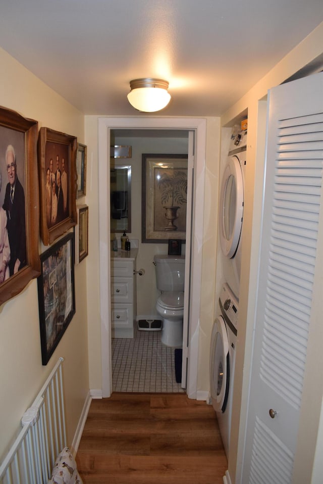 laundry room with stacked washing maching and dryer and dark hardwood / wood-style flooring