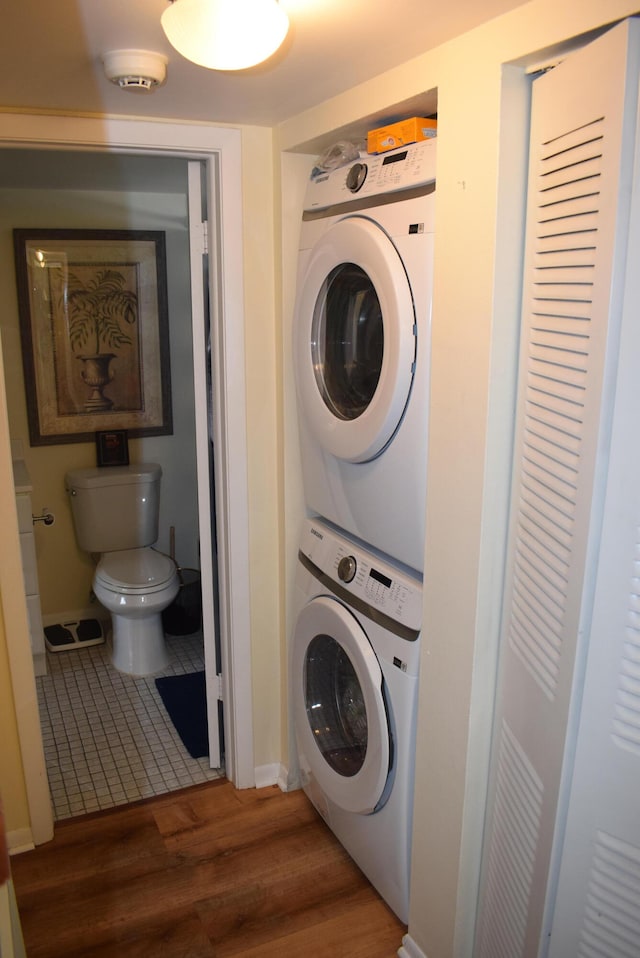 laundry area with stacked washing maching and dryer and dark wood-type flooring