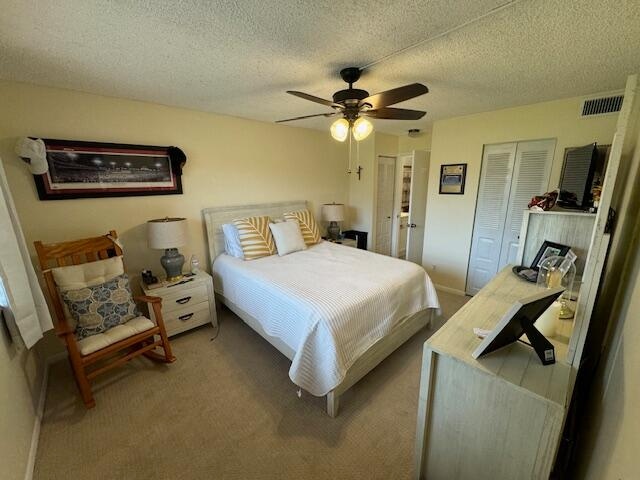 carpeted bedroom featuring a closet, a textured ceiling, and ceiling fan