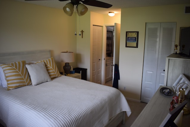 bedroom with ceiling fan, a textured ceiling, carpet floors, and two closets