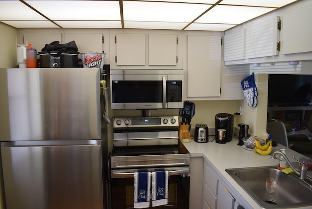 kitchen with stainless steel appliances, sink, and white cabinets