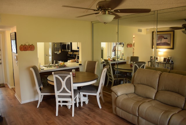 dining room featuring a textured ceiling, hardwood / wood-style flooring, and ceiling fan