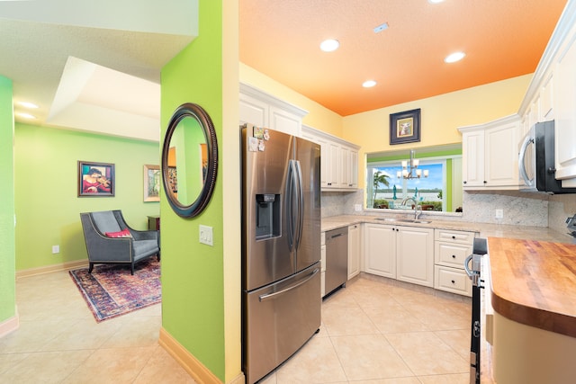 kitchen with appliances with stainless steel finishes, white cabinetry, and wooden counters