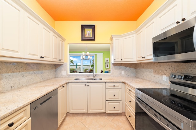 kitchen with light stone counters, light tile patterned floors, appliances with stainless steel finishes, an inviting chandelier, and sink