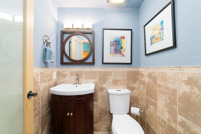 bathroom with tile walls, vanity, a textured ceiling, and toilet