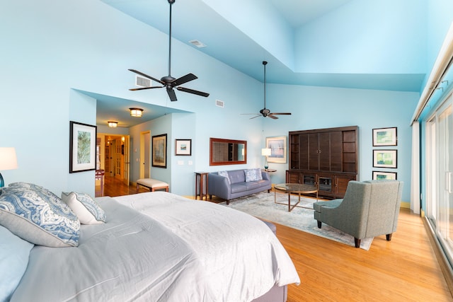 bedroom with light hardwood / wood-style floors, high vaulted ceiling, multiple windows, and ceiling fan