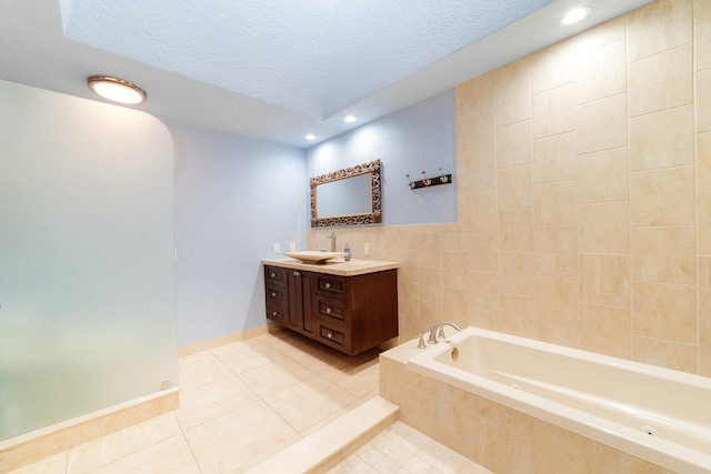 bathroom with vanity, a textured ceiling, tiled tub, and tile patterned flooring