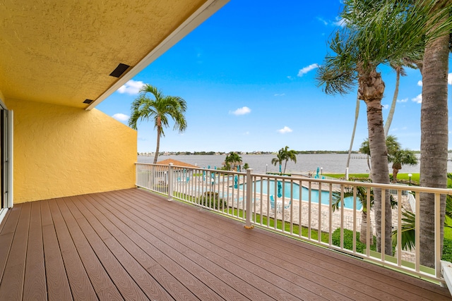 wooden deck featuring a fenced in pool and a water view