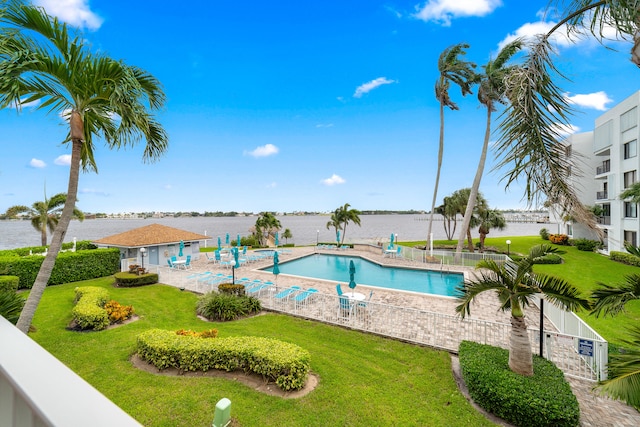 view of pool with a patio, a yard, and a water view