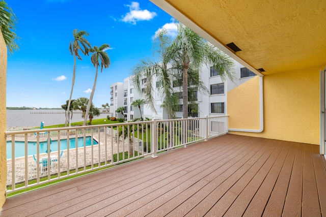 wooden terrace with a water view and a fenced in pool