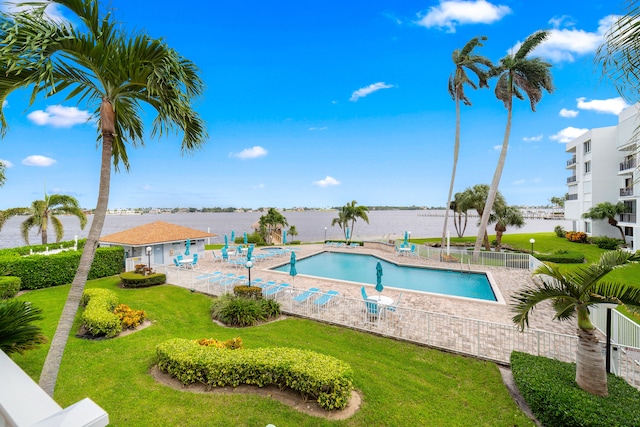 view of swimming pool with a patio, a lawn, and a water view