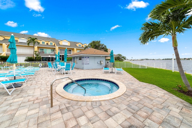 view of pool with a patio, a community hot tub, a yard, and a water view