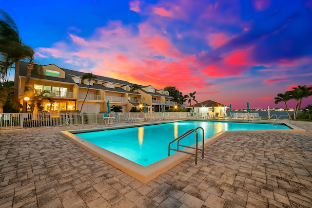 pool at dusk with a patio area