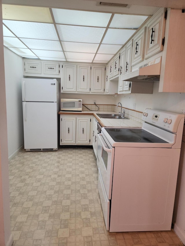 kitchen featuring sink, custom exhaust hood, white appliances, and a paneled ceiling