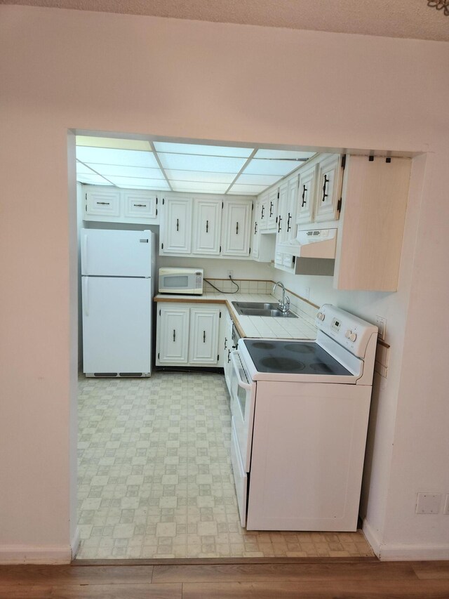 kitchen with white appliances, sink, and white cabinets