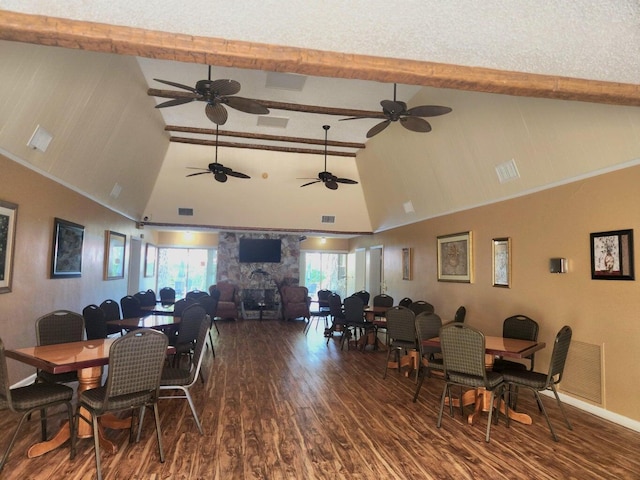 dining area with beamed ceiling, dark wood-type flooring, a stone fireplace, and high vaulted ceiling