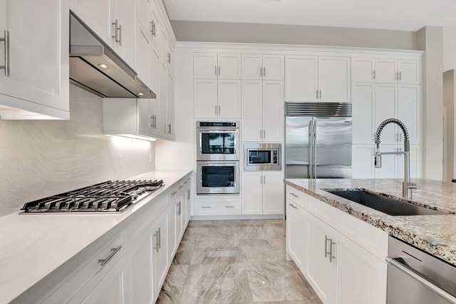 kitchen with white cabinets, built in appliances, light stone counters, and sink