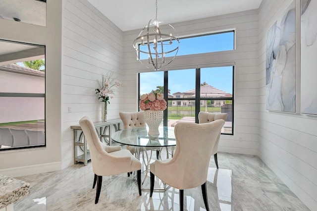 dining area with wood walls and an inviting chandelier