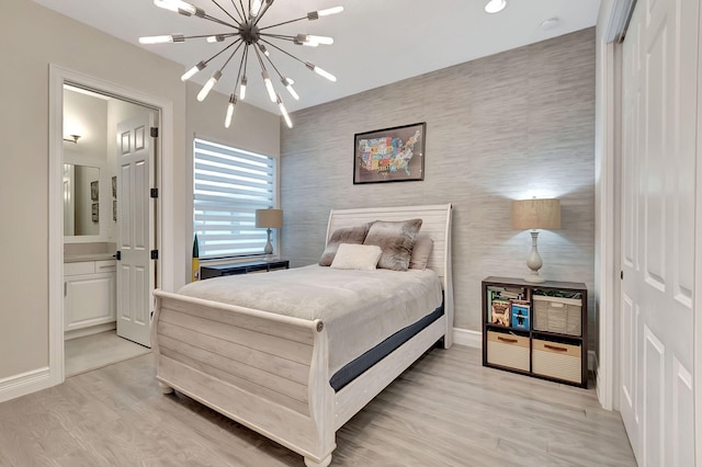 bedroom with connected bathroom, a closet, an inviting chandelier, and light wood-type flooring