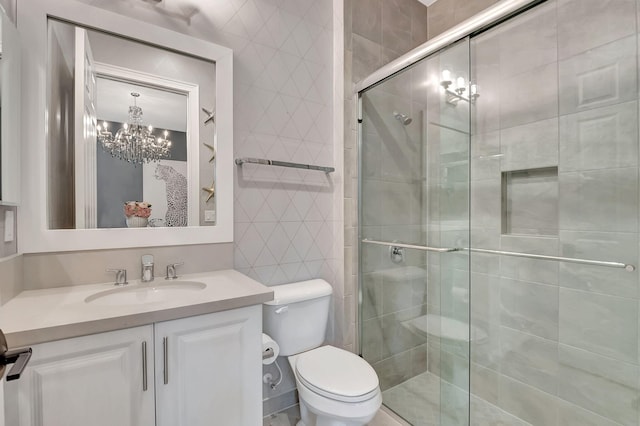 bathroom featuring an inviting chandelier, vanity, a shower with shower door, and toilet