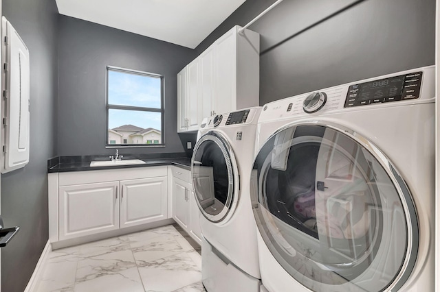 clothes washing area with cabinets, washer and clothes dryer, and sink