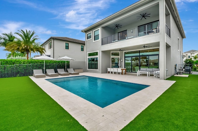 back of property with a balcony, outdoor lounge area, ceiling fan, a patio, and a fenced in pool