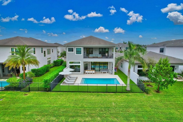 rear view of property with outdoor lounge area, a fenced in pool, a balcony, a yard, and a patio