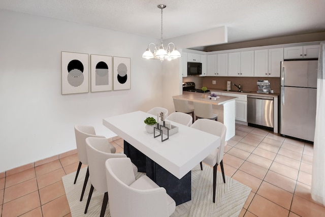 dining area featuring a textured ceiling, light tile patterned floors, sink, and a notable chandelier