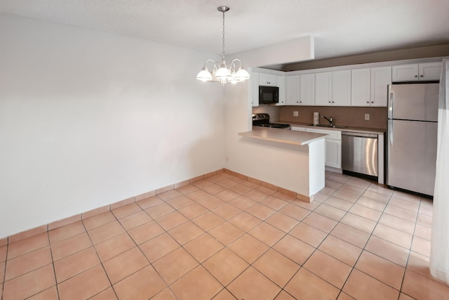 kitchen featuring appliances with stainless steel finishes, decorative light fixtures, white cabinetry, sink, and kitchen peninsula