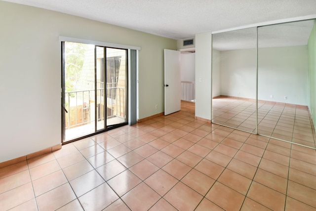 tiled empty room with a textured ceiling