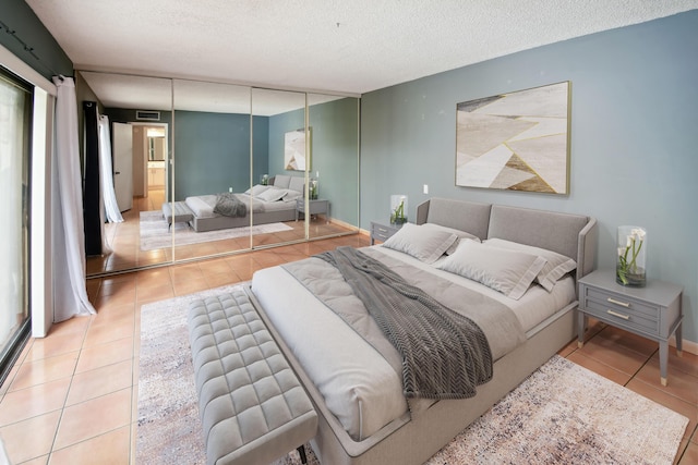 bedroom featuring a textured ceiling, a closet, light tile patterned flooring, and multiple windows