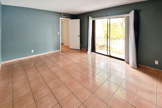 empty room with light tile patterned floors and a textured ceiling