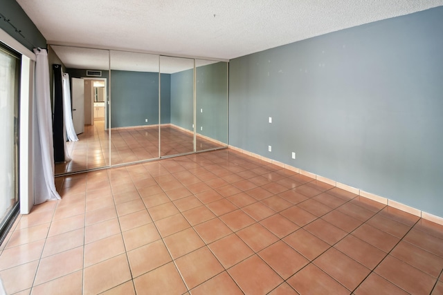 unfurnished bedroom featuring a textured ceiling, light tile patterned floors, and a closet