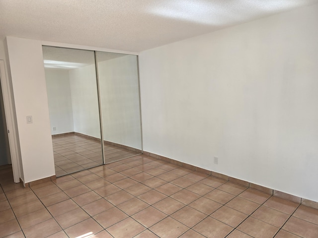 unfurnished bedroom featuring a textured ceiling, a closet, and light tile patterned floors