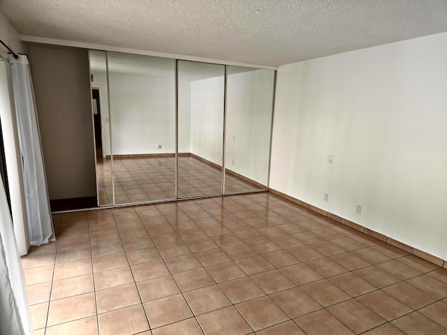 unfurnished bedroom with a textured ceiling, a closet, and light tile patterned flooring