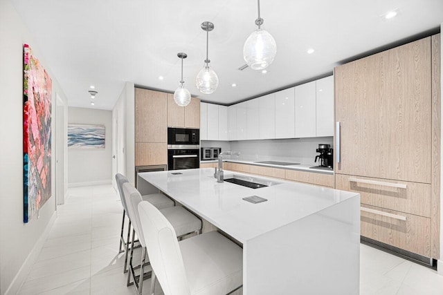 kitchen with sink, white cabinetry, decorative light fixtures, a breakfast bar area, and a kitchen island with sink