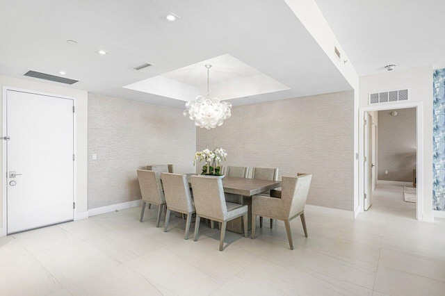 dining space with a tray ceiling and a chandelier