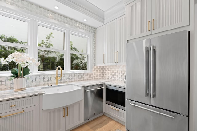 kitchen with sink, appliances with stainless steel finishes, light wood-type flooring, and tasteful backsplash