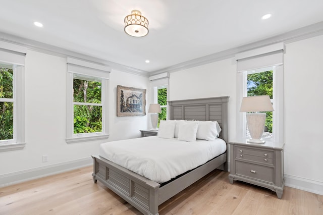 bedroom with light hardwood / wood-style flooring, ornamental molding, and multiple windows