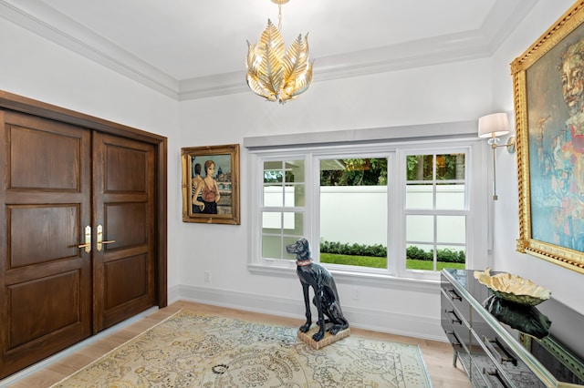 entryway featuring an inviting chandelier, crown molding, and light hardwood / wood-style floors