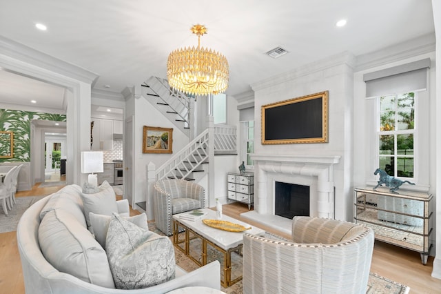 living room with crown molding, an inviting chandelier, and light wood-type flooring