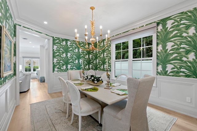 dining space with ornamental molding, a chandelier, and light wood-type flooring