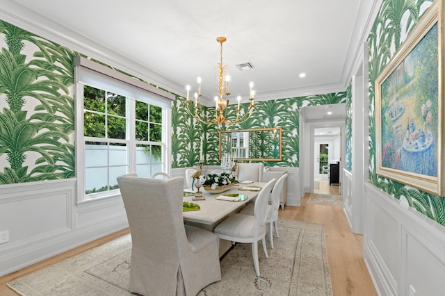 dining room with crown molding, light hardwood / wood-style flooring, and an inviting chandelier