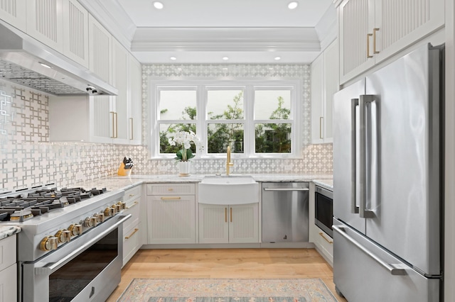 kitchen with high end appliances, backsplash, light hardwood / wood-style floors, and range hood