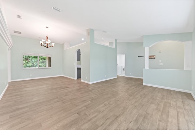 unfurnished living room with a notable chandelier, washer / clothes dryer, lofted ceiling, and light wood-type flooring