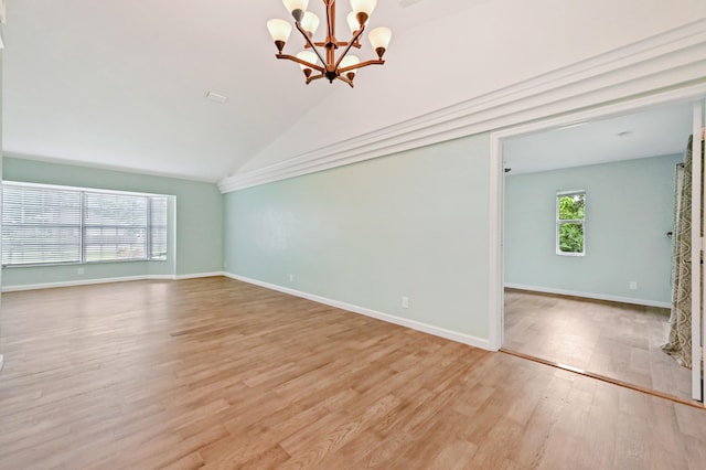 unfurnished living room with light hardwood / wood-style floors, a healthy amount of sunlight, vaulted ceiling, and an inviting chandelier